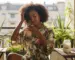 Une femme afro prend soin de ses cheveux naturels en plein air, profitant des bienfaits de la nature pour sa routine capillaire.